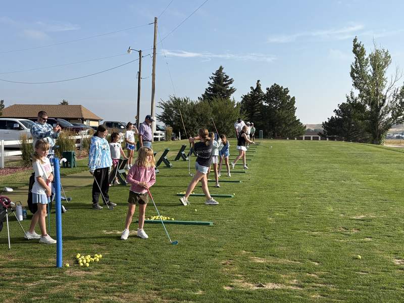Junior golfers practicing on the driving range